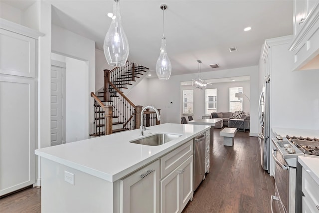 kitchen featuring stainless steel appliances, dark wood-type flooring, sink, a center island with sink, and white cabinets