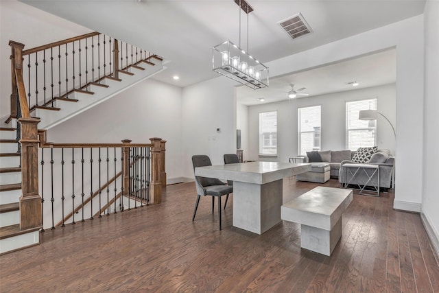 kitchen featuring a kitchen breakfast bar, dark wood-type flooring, a notable chandelier, a center island, and hanging light fixtures