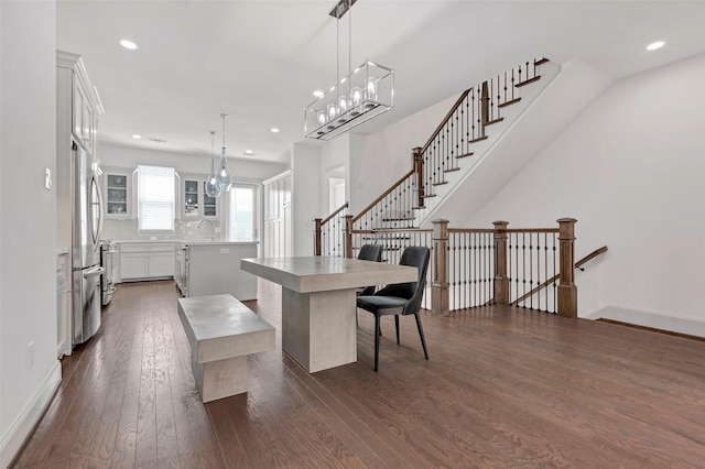 kitchen featuring a kitchen breakfast bar, decorative light fixtures, a center island, dark hardwood / wood-style floors, and white cabinetry