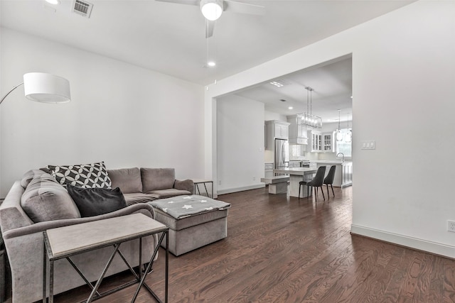 living room featuring ceiling fan, sink, and dark wood-type flooring