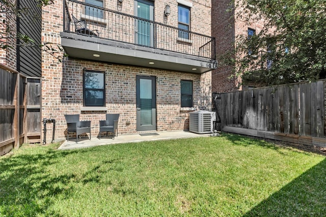 rear view of house featuring a yard, a balcony, a patio, and central air condition unit