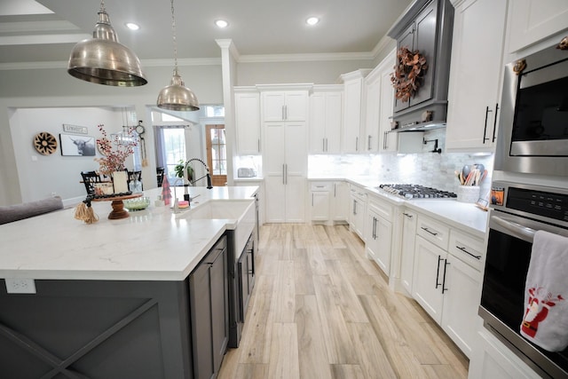 kitchen featuring white cabinets, appliances with stainless steel finishes, light hardwood / wood-style floors, and an island with sink