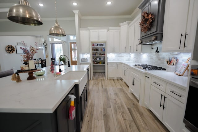 kitchen with appliances with stainless steel finishes, light hardwood / wood-style floors, white cabinetry, and an island with sink