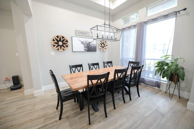 dining space with light hardwood / wood-style floors and a notable chandelier