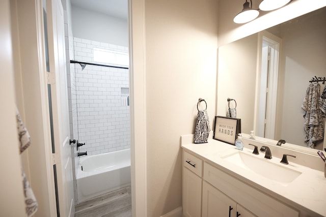 bathroom with hardwood / wood-style floors, vanity, and tiled shower / bath