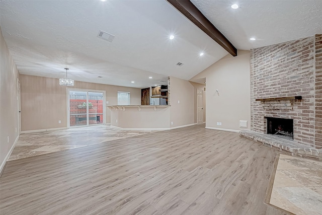 unfurnished living room with vaulted ceiling with beams, a chandelier, a textured ceiling, a fireplace, and light wood-type flooring