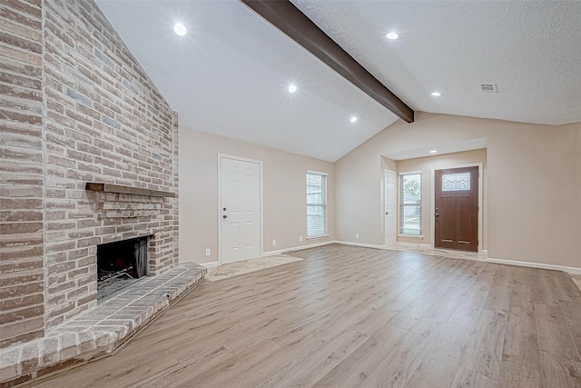 unfurnished living room featuring vaulted ceiling with beams, light wood-type flooring, and a fireplace