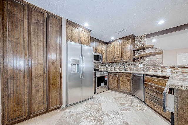 kitchen with backsplash, sink, light stone counters, and stainless steel appliances