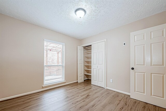 unfurnished bedroom with light hardwood / wood-style floors, a textured ceiling, and a closet