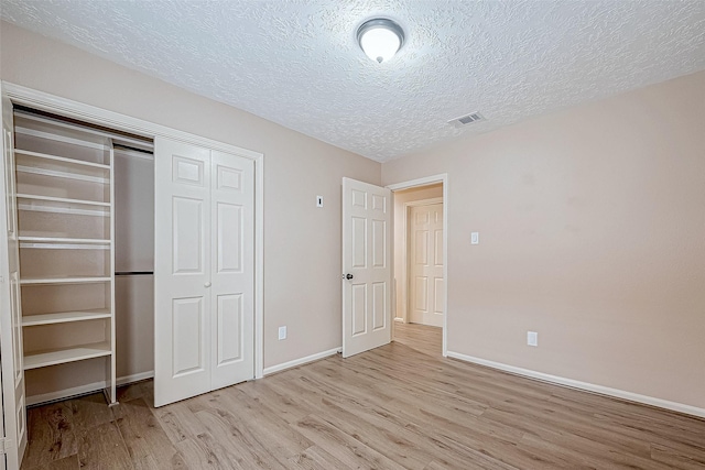 unfurnished bedroom featuring a textured ceiling, light hardwood / wood-style flooring, and a closet