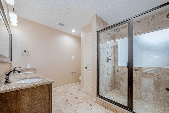 bathroom featuring vanity, a shower with shower door, a textured ceiling, and toilet