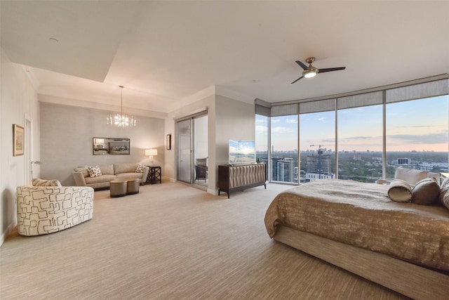 carpeted bedroom featuring ceiling fan with notable chandelier and expansive windows