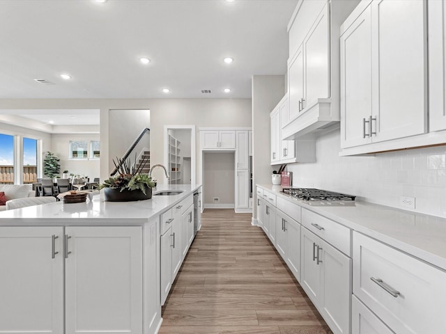 kitchen with sink, white cabinetry, and a kitchen island with sink