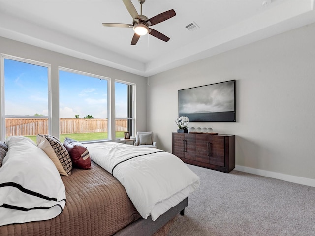 carpeted bedroom with a tray ceiling and ceiling fan