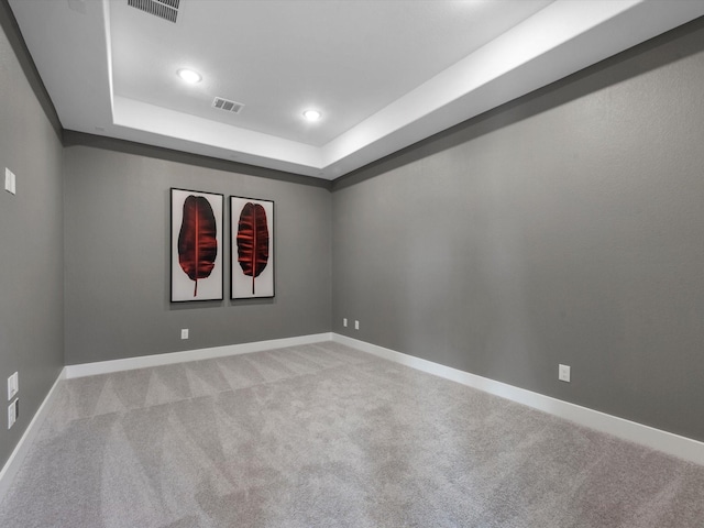 carpeted empty room with a tray ceiling