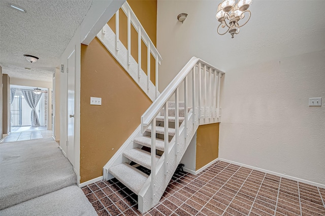 stairway with carpet floors, a textured ceiling, and an inviting chandelier