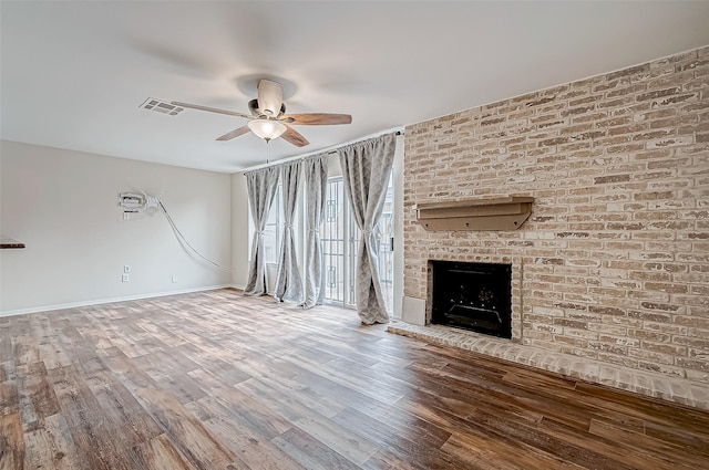 unfurnished living room featuring ceiling fan, hardwood / wood-style floors, and a brick fireplace