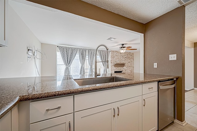 kitchen with a textured ceiling, white cabinetry, dark stone countertops, and sink