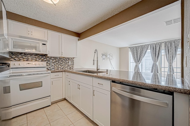 kitchen featuring white appliances, backsplash, sink, light tile patterned flooring, and white cabinetry