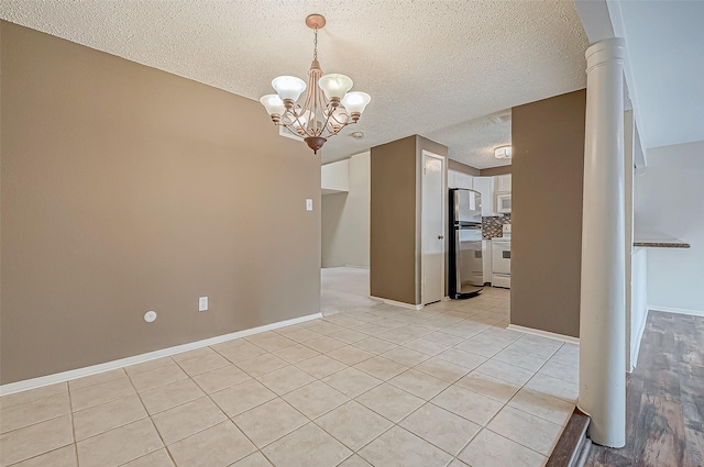 empty room with light tile patterned floors, a chandelier, and a textured ceiling