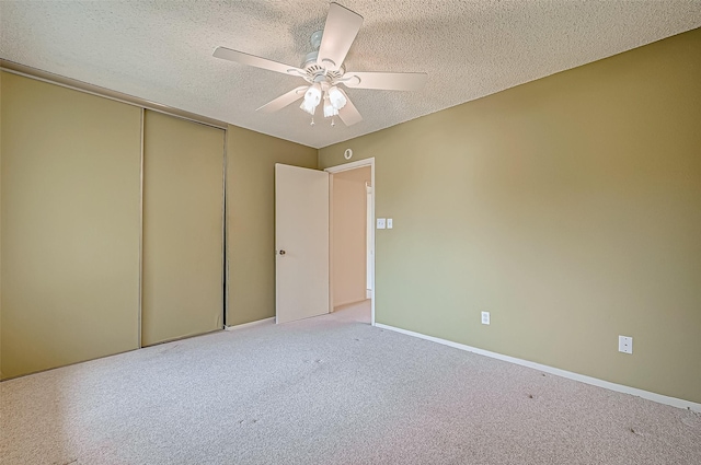 unfurnished bedroom with ceiling fan, a closet, light colored carpet, and a textured ceiling