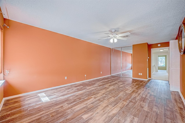 spare room with a textured ceiling, light hardwood / wood-style flooring, and ceiling fan