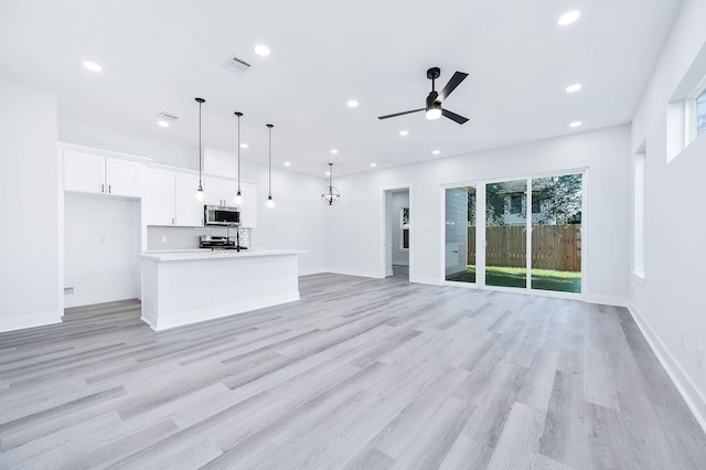 unfurnished living room featuring ceiling fan, sink, and light hardwood / wood-style flooring