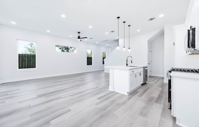 kitchen with white cabinets, an island with sink, light hardwood / wood-style floors, and decorative light fixtures