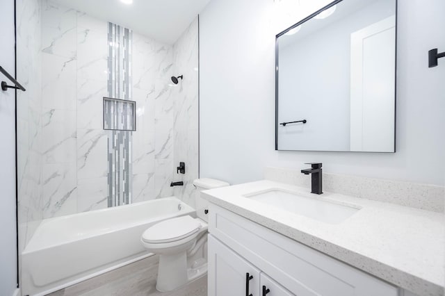 full bathroom featuring hardwood / wood-style floors, vanity, tiled shower / bath combo, and toilet