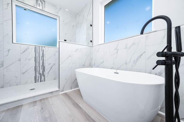 bathroom featuring hardwood / wood-style floors, a wealth of natural light, independent shower and bath, and tile walls