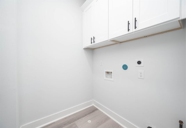 washroom featuring hookup for an electric dryer, washer hookup, light hardwood / wood-style floors, and cabinets