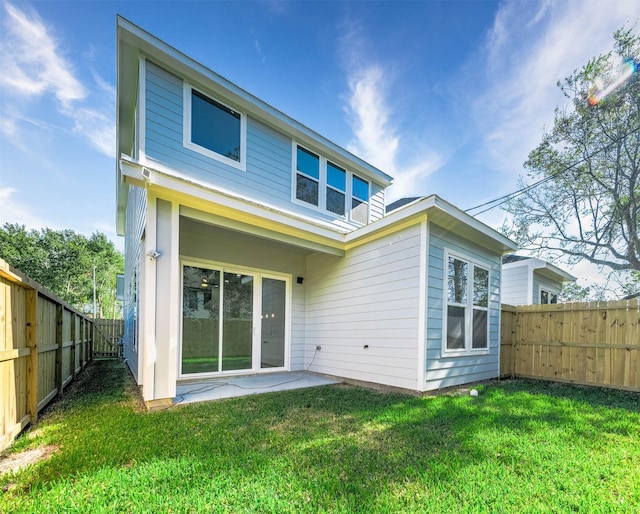 rear view of property featuring a lawn and a patio area