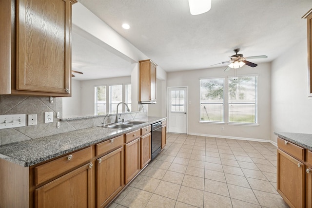 kitchen featuring ceiling fan, dishwasher, sink, tasteful backsplash, and dark stone counters