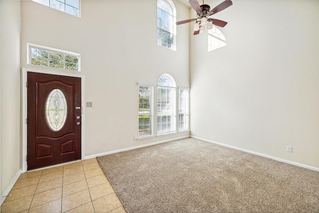 carpeted foyer entrance featuring a high ceiling and a healthy amount of sunlight