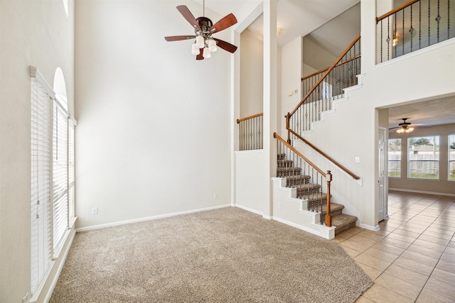 interior space with carpet, ceiling fan, and a towering ceiling