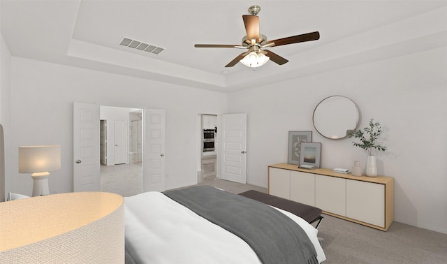 bedroom with ceiling fan, a raised ceiling, and light colored carpet