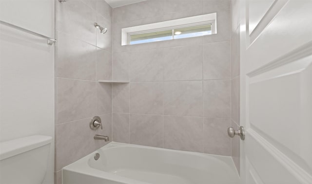 bathroom with toilet and tiled shower / bath