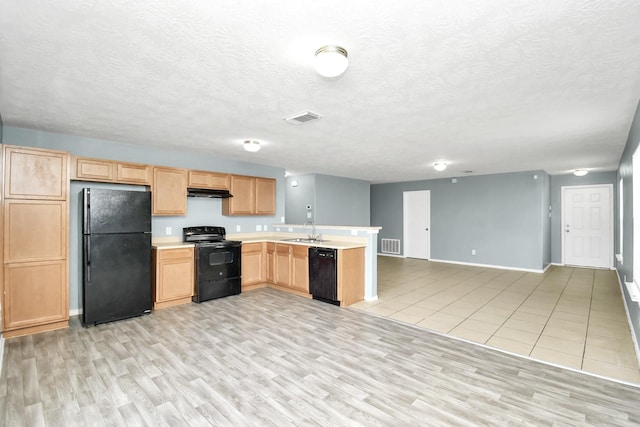 kitchen with light brown cabinets, black appliances, sink, light wood-type flooring, and a textured ceiling