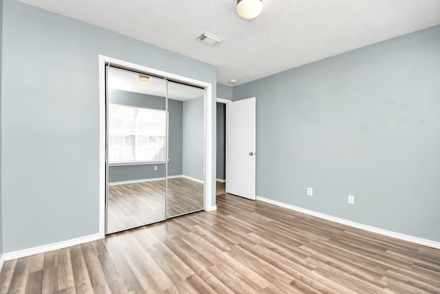 unfurnished bedroom featuring a closet, a textured ceiling, and light wood-type flooring