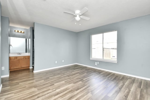 unfurnished bedroom featuring ensuite bathroom, light hardwood / wood-style flooring, ceiling fan, and sink