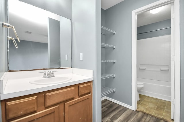 full bathroom featuring hardwood / wood-style floors, vanity, toilet, and  shower combination