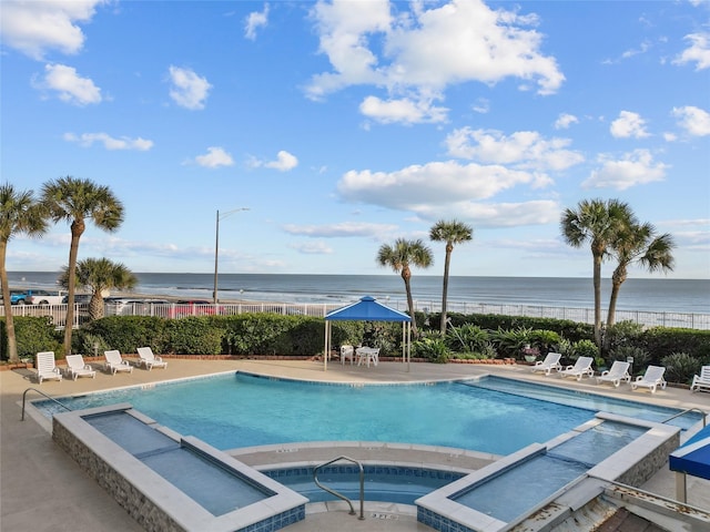 view of pool with a community hot tub, a water view, and a patio area