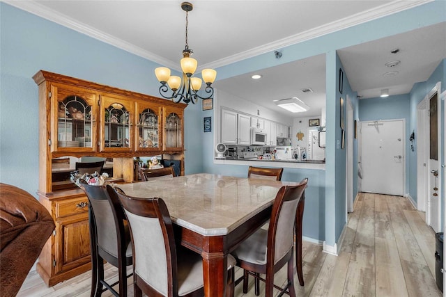 dining space featuring ornamental molding, light hardwood / wood-style floors, and a notable chandelier