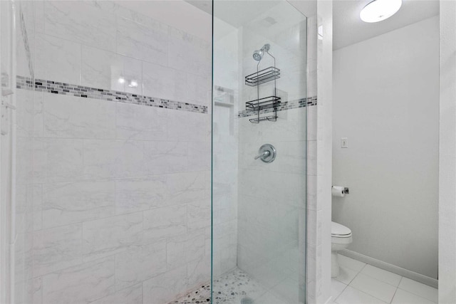 bathroom with tiled shower, tile patterned flooring, and toilet