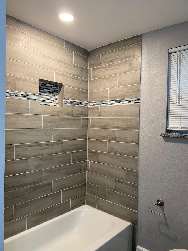 bathroom with toilet and tiled shower / bath