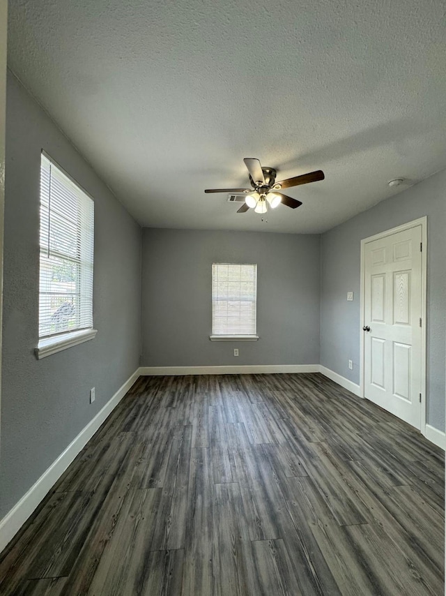 unfurnished room with a textured ceiling, dark hardwood / wood-style floors, and a healthy amount of sunlight