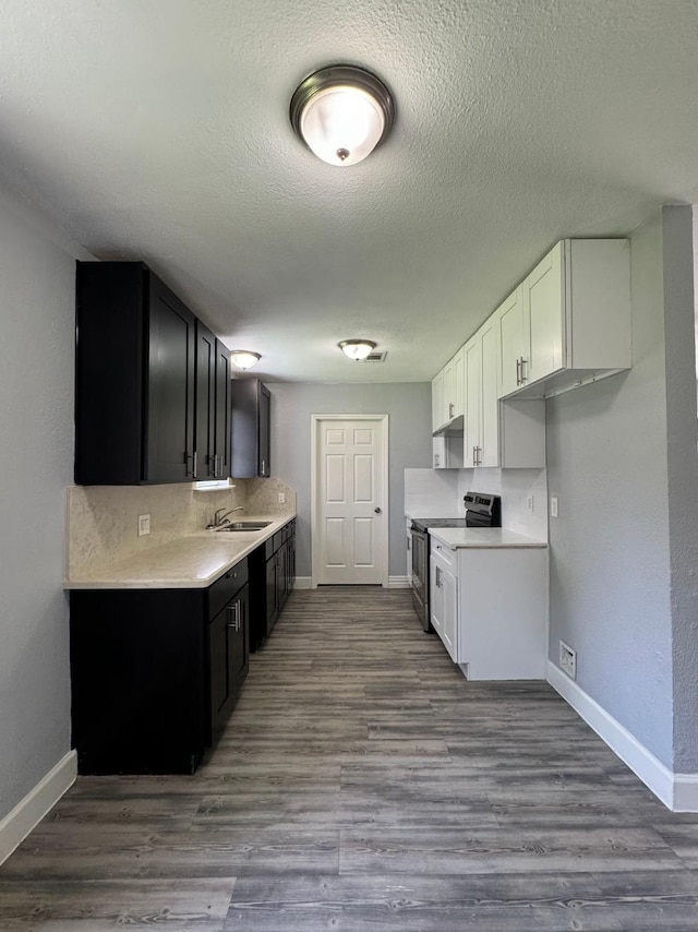 kitchen with white cabinetry, wood-type flooring, electric stove, and a textured ceiling