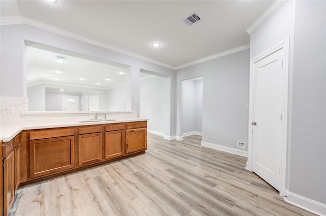 kitchen with kitchen peninsula, crown molding, sink, light hardwood / wood-style flooring, and lofted ceiling