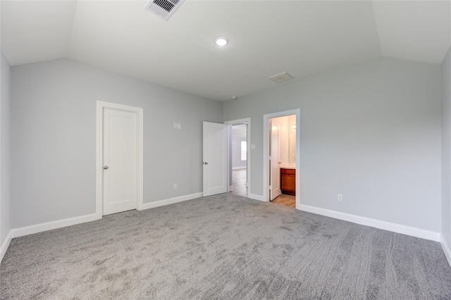 unfurnished bedroom with lofted ceiling, light carpet, connected bathroom, and a closet