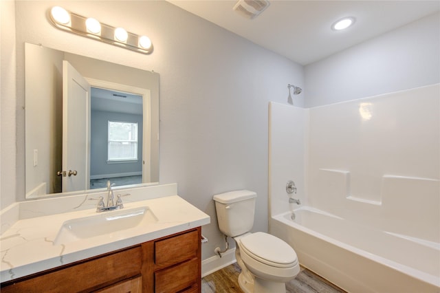 full bathroom featuring washtub / shower combination, vanity, hardwood / wood-style flooring, and toilet